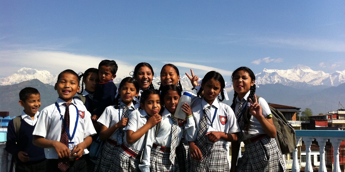 Nepal school children smiling with the Himalayas behind them